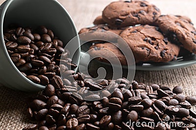 Coffee beans crumbled with a cup, in the background a plate of cookies Stock Photo