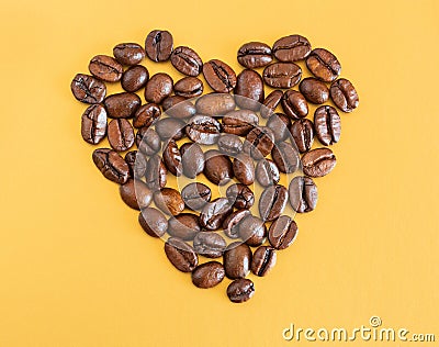 Coffee beans and dried oranges on a yellow background. Heart made of coffee beans. Love for coffee. Stock Photo