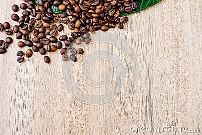 Coffee beans on a green leaf and scattered on a light wooden table, top view, closeup grains, flat lay, copy space Stock Photo
