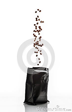 Coffee beans isolated on a white background are poured into a black packet Stock Photo