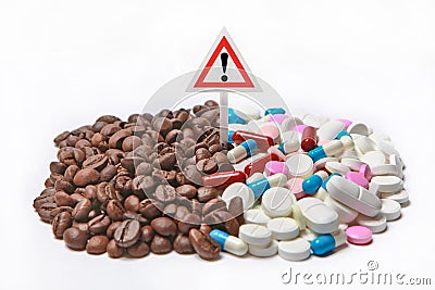 Coffee beans next to medicines and a warning exclamation mark. Stock Photo