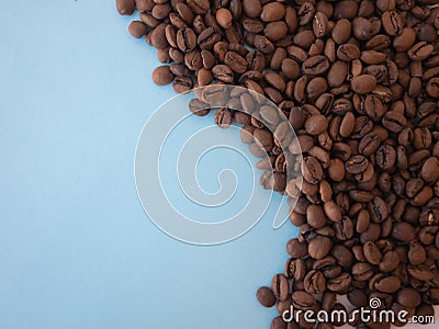 Coffee beans scattered on blue in a wave shape, space for text and copy space Stock Photo