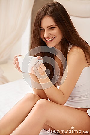 Coffee. Beautiful Girl Drinks Tea or Coffee Sitting on Bed Stock Photo