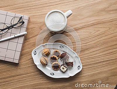 Coffee break - a mug of coffee with milk, cookies, a notebook on a wooden table, top view Stock Photo