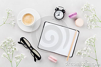 Coffee, cake macaron, notebook, eyeglasses, alarm clock and flower for breakfast on table top view. Woman working desk. Flat lay. Stock Photo