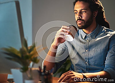 Coffee can be the perfect solution when youre losing steam. a young designer working late in an office. Stock Photo