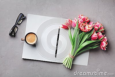 Coffee, clean notebook, eyeglasses and beautiful flower on stone table top view in flat lay style. Woman working desk. Stock Photo