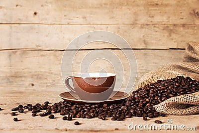 Coffee cup, beans and a burlap bag on old wooden background Stock Photo