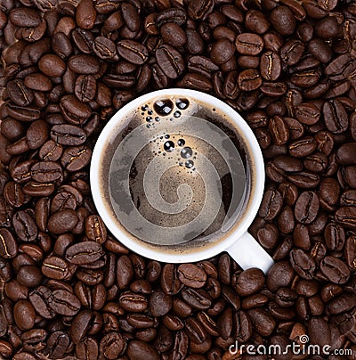 Coffee cup with black freshly brewed coffee among coffee beans. Stock Photo