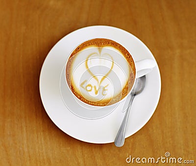 Coffee cup, cappuccino and heart in foam on a table with no people in a restaurant and diner. Cafe drink, love writing Stock Photo