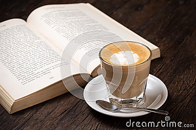 Coffee cup cappuccino hot latte or coffee with milk in a glass cup, open book Stock Photo