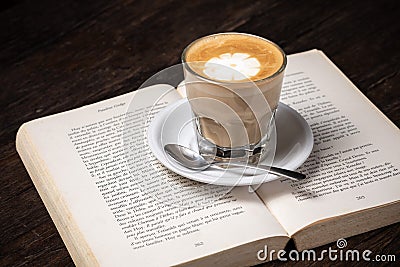 Coffee cup cappuccino hot latte or coffee with milk in a glass cup, open book Stock Photo