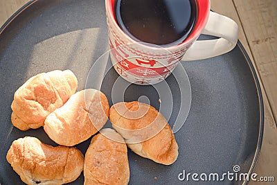 Coffee in a cup and croissants on a plate. Food and drinks. Plate on a wooden background Stock Photo