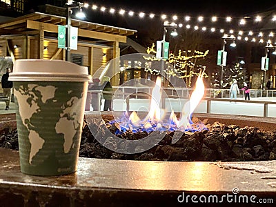 Coffee cup in front of fire rink at ski resort Stock Photo