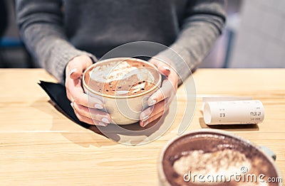Coffee cup between hands in cafe in winter. Cappuccino, macchiato, latte or hot chocolate cocoa. Two persons having a warm meeting Stock Photo