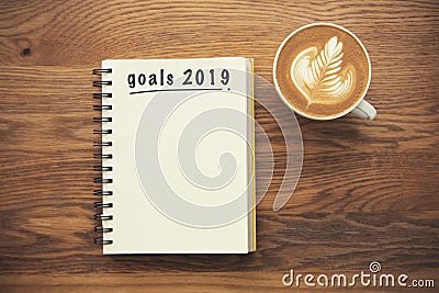 Coffee cup and notebook with goals 2019 on rustic desk Stock Photo