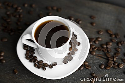 Coffee cup with roasted coffee beans on wooden table background. Mug of black coffe with scattered coffee beans on a Stock Photo