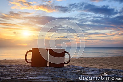 Coffee cup on wood log at sunset or sunrise beach Stock Photo