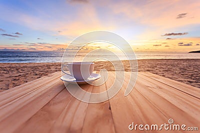 Coffee cup on wood table at sunset or sunrise beach Stock Photo