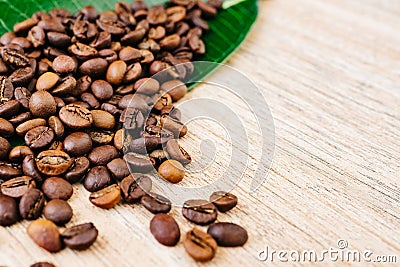 Coffee on a green leaf and scattered on a light wooden table, top view, closeup grains, place to insert text, copy space Stock Photo