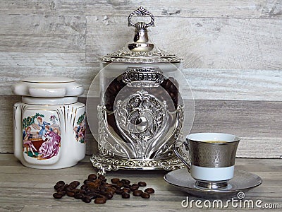 Coffee jars and a cup of coffee on bleached oak wooden shelf porcelain and glass silver vintage sterling. Stock Photo