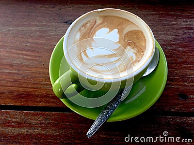 Coffee in lime green cup and saucer. Art Latte. Stock Photo