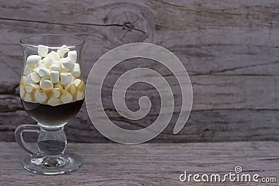 Coffee And Many Small Marshmallows In A Transparent Glass Cup On A Wooden Background. The Photo In Cold Colors Stock Photo