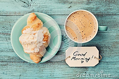 Coffee mug with croissant and notes good morning on turquoise rustic table from above, cozy and tasty breakfast Stock Photo