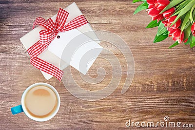 Coffee mug, present box with blank paper tag and tulips on rustic wooden table. Top view. Breakfast on Valentine, Mother or Womens Stock Photo