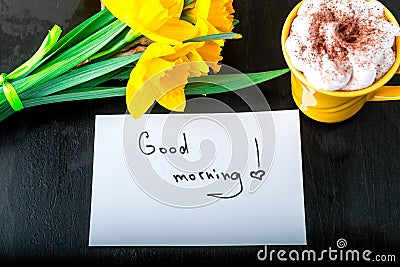 Coffee mug with yellow daffodil flowers and quotes good morning on white rustic table. Mothers day or Womens day. Greeting card. T Stock Photo