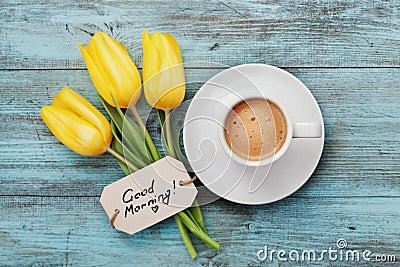 Coffee mug with yellow tulip flowers and notes good morning on blue rustic table from above Stock Photo