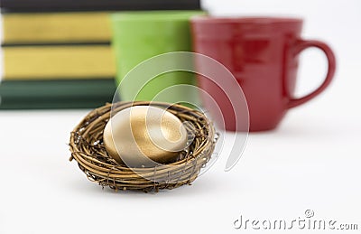 Coffee mugs, books, and gold nest egg Stock Photo