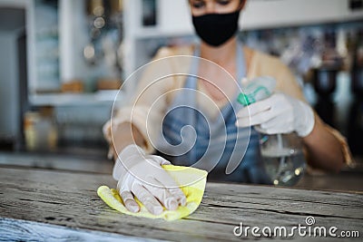 Coffee shop woman owner working with face mask and gloves , disinfecting counter. Stock Photo