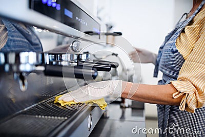 Coffee shop woman owner working with gloves , disinfecting machine. Stock Photo