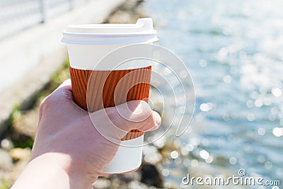 Coffee single cup in hand on the background of the lake in bokeh Stock Photo