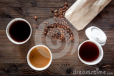 Coffee take away. Coffee cups with covers and coffee beans on wooden table backound top view Stock Photo