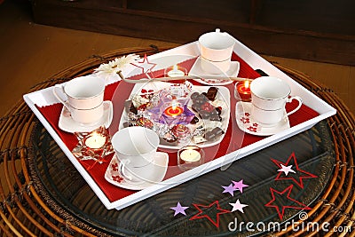 Coffee or tea party setup with decor, candles and chocolates and sweets on a tray with cups and saucers Stock Photo