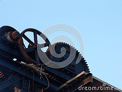 Cogs big metal structure, with dried wooden branches hanging, standing against the blue sky in Tel Aviv port, Israel Stock Photo