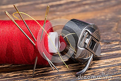 Coil thread and shuttle from the sewing machine, on a wooden table Stock Photo