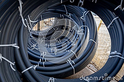 Coils of black polyethylene pipes for laying high voltage electrical cables underground at a construction site Stock Photo