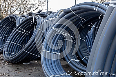 Coils of black polyethylene pipes for laying high voltage electrical cables underground at a construction site Stock Photo