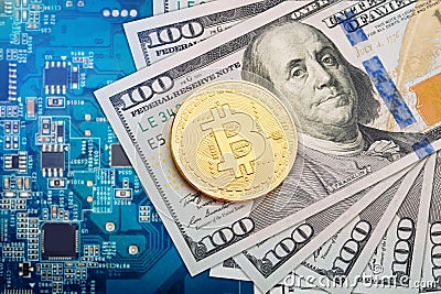 The coin of bitcoin lies on dollars against the background of the video card. Stock Photo