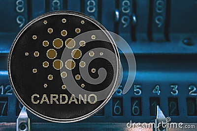 Coin cryptocurrency ADA against the numbers of the arithmometer. Cardano Editorial Stock Photo