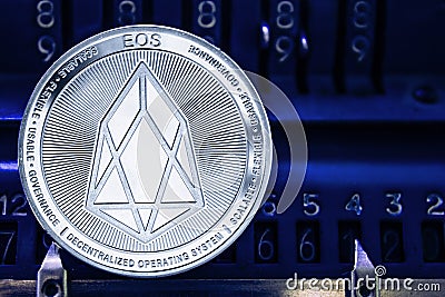 Coin cryptocurrency EOS against the numbers of the arithmometer. Editorial Stock Photo