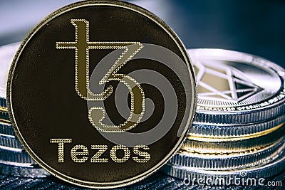 Coin cryptocurrency Tezos XTZ on the background of a stack of coins. MKR Stock Photo