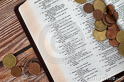 Coin money on open Holy Bible, concept of Christian tithing, offering, religious contribution Stock Photo