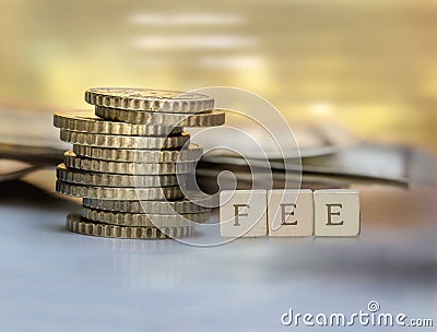 Coin stack and wooden blocks with the fee text. Stock Photo