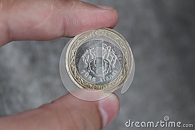 A coin worth 1 Turkish lira between the fingers of the hand Stock Photo