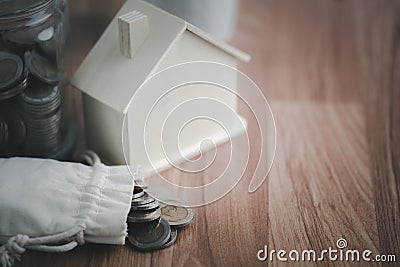 The coins are in the cloth bag and the replica wooden houses are all on the table. Stock Photo