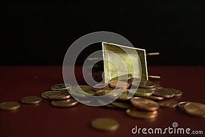 Coins falling from a golden vintage wheelbarrow. Stock Photo